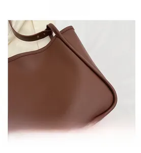 Detailed macro view of the smooth dark brown leather texture and stitching on this tote bag