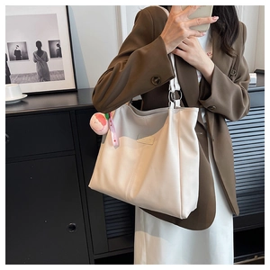 Dettaglio della borsa tote crema con logo in rilievo e anelli in metallo argentato