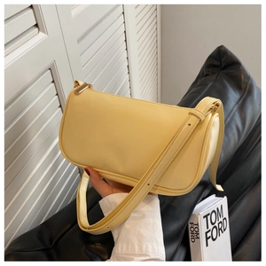 Close-up of a minimalist pale yellow baguette bag featuring smooth texture and gold zipper