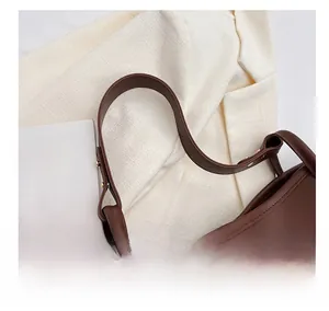 Detail of wide shoulder strap on brown faux leather tote bag with carrot charm