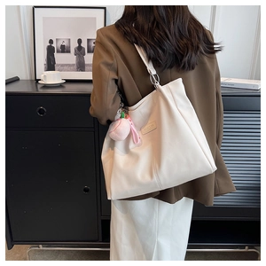 Dettaglio della borsa tote in pelle PU crema con design a pieghe e ciondolo di peluche