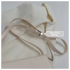 Close-up of adjustable cream leather shoulder strap with silver metal buckle detail