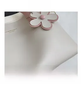 Close-up of white leather tote texture with pink flower charm and fashion lettering