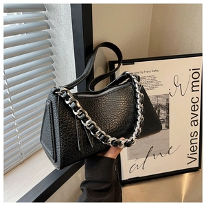 Detalle del bolso tipo almohada en cuero negro texturizado con cadena de metal plateada