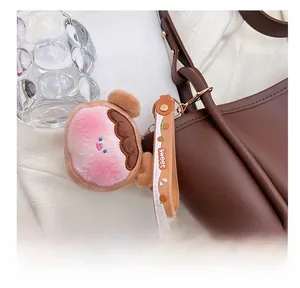 Detail showing a cute pink plush charm with Sweet silicone strap on a brown tote bag