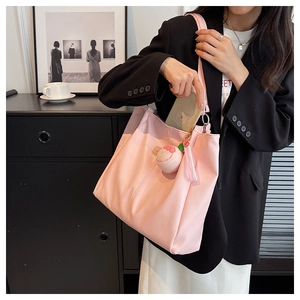 Dettaglio della borsa tote rosa con ciondolo a pesca e ampio interno in uso