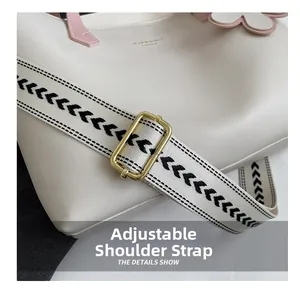 Detail of adjustable geometric patterned strap with gold buckle on a beige tote bag