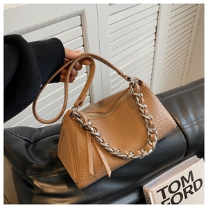 Primer plano de bolso marrón con textura de grano lichi, cadena plateada y bandolera