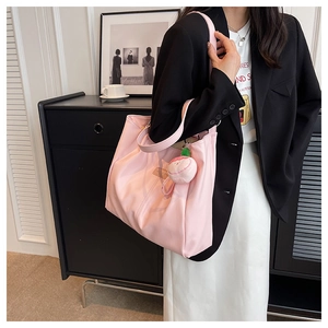 Borsa tote in nylon rosa con ciondolo di peluche in un ambiente interno moderno