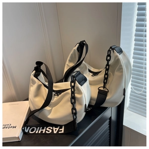 Detail of white leather crescent bag with 'FASHION' strap and black decorative chain