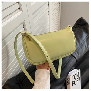 Detail of avocado green leather shoulder bag with fine stitching and gold zipper
