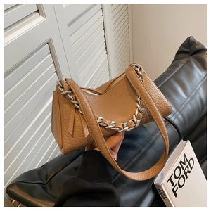 Detalle de bolso de cuero marrón con textura de lichi y cadena de metal plateado