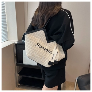 Détail d'un sac cabas en paille beige avec bordure en cuir noir et broderie Summer