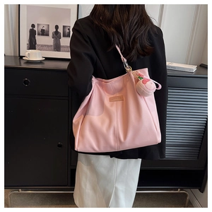 Dettaglio di una borsa tote rosa capiente con ciondolo a fragola per il pendolarismo