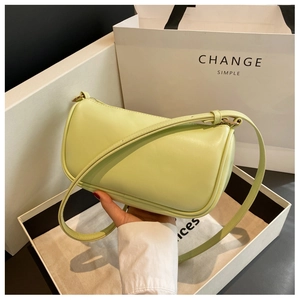Detail showing mint green leather pillow bag held by hand next to luxury gift packaging
