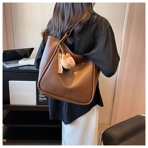 Close-up of brown large tote bag featuring hobo style leather texture and peach charm