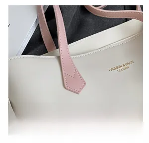 Detail showing the fine stitching and golden logo on the cream leather tote bag