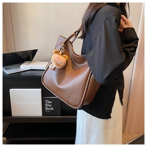 Brown leather tote bag for work with cute bear pendant shown in office setting