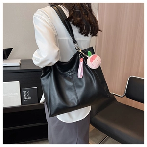 Dettaglio della borsa tote nera in similpelle con logo metallico e ciondolo a pesca