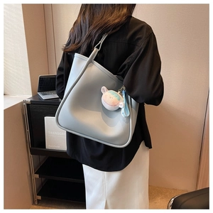 Detail of light blue tote bag with matte leather finish and cute plush charm