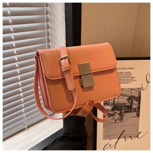 Detailed view of pink rectangular crossbody bag with silver striped push-lock and leather strap