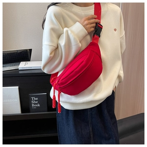 Close-up of a stylish red canvas crescent fanny pack worn across the chest by a model