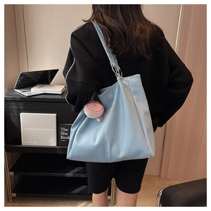 Dettaglio della grande borsa tote celeste con trama in pelle e ciondolo di peluche