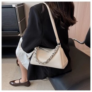 Detalle de bolso bajo el brazo blanco crema con textura de cocodrilo y cadena plata