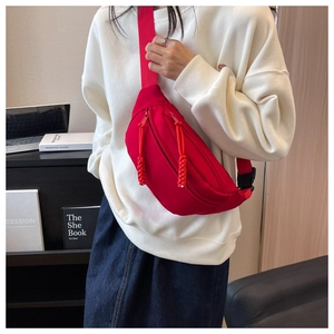 Detailed view of a red canvas fanny pack with dual zippers worn across the chest