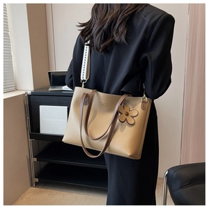 Detail of beige tote bag with brown handles and a stylish geometric wide strap