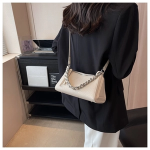 Detalle de bolso de hombro en cuero texturizado blanco crema con cadena de plata