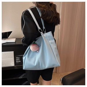Dettaglio della borsa shopper azzurra con ciondolo a pesca e connettori ad anello metallici