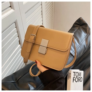Detail of tan rectangle crossbody bag with silver buckle and adjustable strap