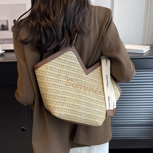 Sac fourre-tout en paille avec broderie Summer et large bandoulière porté par un mannequin