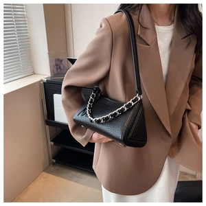 Detalle de bolso acolchado de cuero granulado negro con cadena de plata en modelo