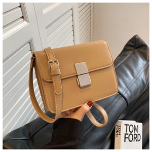 Detail of light brown PU leather crossbody bag with silver textured metal push-lock closure