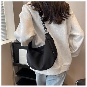 Detail of minimalist black half-moon bag featuring a thick chunky chain shoulder strap
