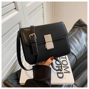 Detail of minimalist black matte leather crossbody bag with silver textured push-lock closure