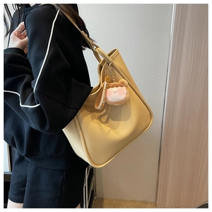 Beige tote bag detail showing smooth faux leather texture and pink plush charm accessory