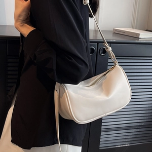 Cream white minimalist semi-circle crossbody bag with adjustable strap worn by model