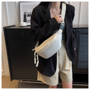 Detail of minimalist canvas chest bag with adjustable strap and plastic buckle on a model