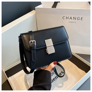 Detail of black crossbody bag with silver metal lock and textured matte finish leather