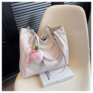 Dettaglio della borsa tote in pelle PU bianca con ciondolo a forma di pesca peluche