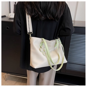 Detail of cream tote bag with light green handles, floral charm and patterned wide strap