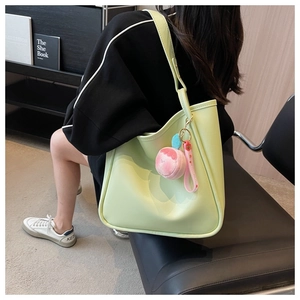 Detail of light green tote bag with smooth leather finish and cute peach plush pendant