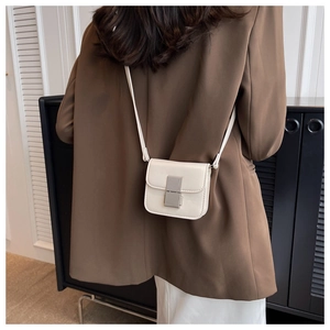 Rear view of a model wearing a premium white leather mini crossbody bag with silver buckle