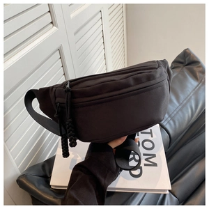Detail of black canvas crossbody bag with multiple zipper pockets and adjustable strap