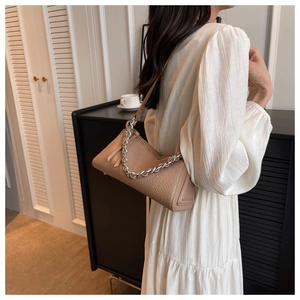 Chic beige lychee grain leather underarm bag with silver chain on model in home setting