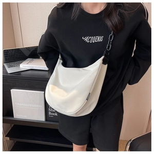 Detail showing white crescent crossbody bag with black chain strap and fashion label