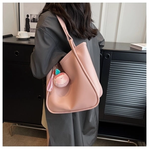 Pink tote bag detail with plush charm and long shoulder strap in a minimalist setting